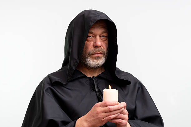 Elderly bearded monk holding lit candle isolated on white background