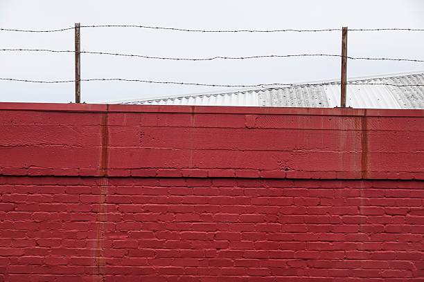 Red brick wall with barbed wire security fence