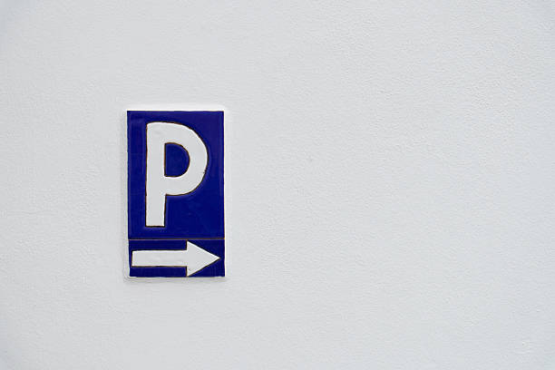 Blue and white parking sign indicating direction with a right arrow on a textured white wall background