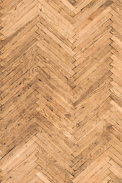 Close-up view of herringbone wooden parquet floor highlighting fine wood grain and craftsmanship details. Premium interior texture ideal for luxury branding, high-end design projects, material presentations and elegant background use. Warm tones and tight framing emphasize quality, texture depth and refined surface aesthetics.