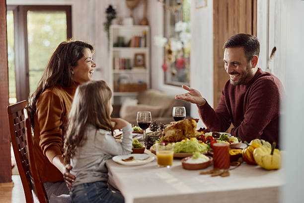 Happy parents enjoying while having lunch with their small girl in dining room.