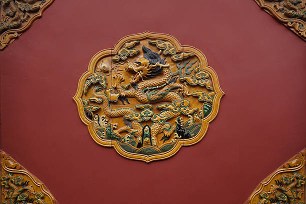 Close-up of a Chinese traditional dragon relief decoration on a red background. Intricate carving of a mythical dragon with floral and cloud patterns, showcasing traditional craftsmanship in the The Forbidden City.