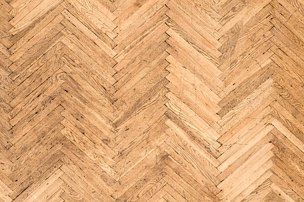 Close-up view of herringbone wooden parquet floor highlighting fine wood grain and craftsmanship details. Premium interior texture ideal for luxury branding, high-end design projects, material presentations and elegant background use. Warm tones and tight framing emphasize quality, texture depth and refined surface aesthetics.