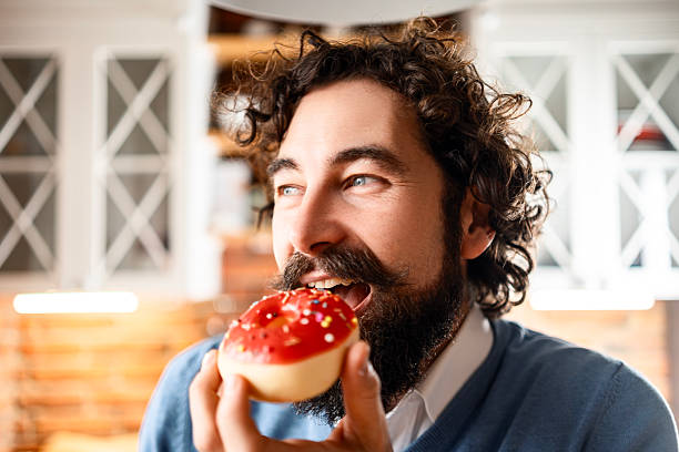 Young Handsome Man Enjoying Sweet Treats With Coffee in Kitchen