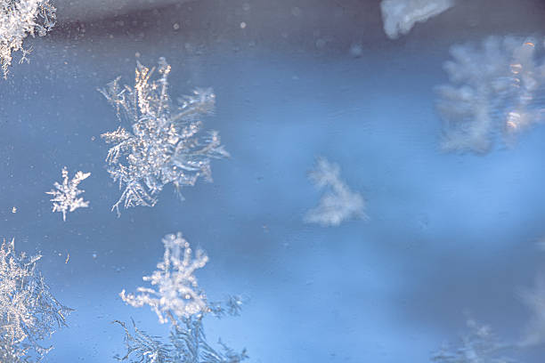 Abstract winter background with delicate frost crystals scattered on window glass. Smooth blue tones, soft natural light and large copy space create a clean, minimal composition ideal for text overlays, banners, headers and seasonal design.