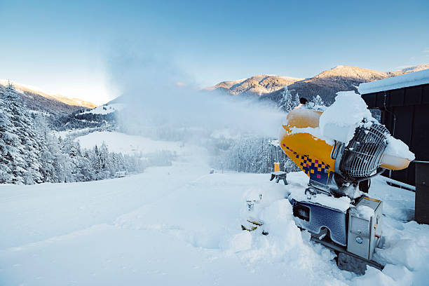 Snow cannon making artificial snow on a ski slope in winter.