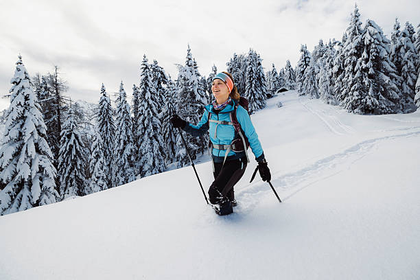 Beautiful woman covered in snow with a candid smile walking through a winter forest. Beautiful natural expression. Real snowflakes falling from the sky. Dynamic shot. Nikon D810. Converted from RAW.