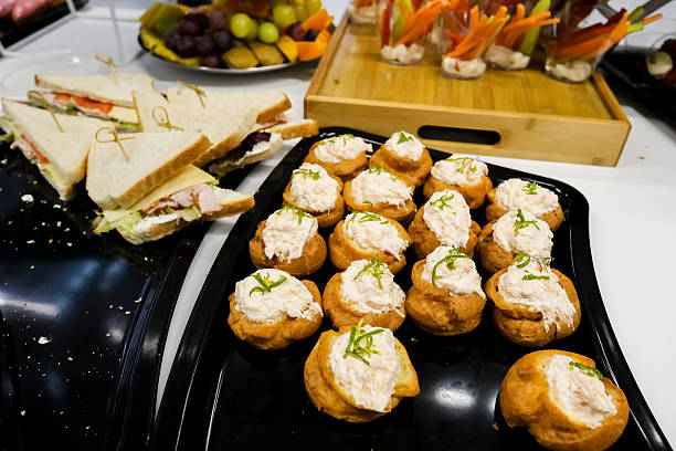 Professional catering display featuring assorted pastries, canapés, fresh vegetables, fruits, and gourmet appetizers elegantly arranged for corporate or celebration event.