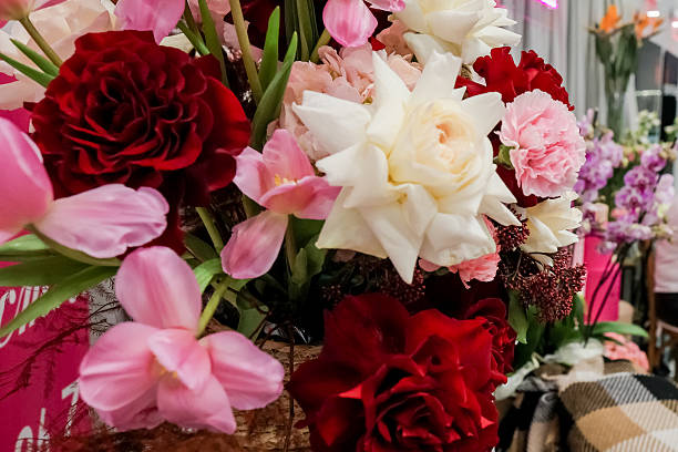 Romantic floral composition featuring red roses, white ranunculus, pink tulips, and carnations in elegant display for special occasions and celebrations.