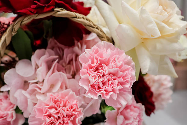 Romantic floral composition featuring red roses, white ranunculus, pink tulips, and carnations in elegant display for special occasions and celebrations.