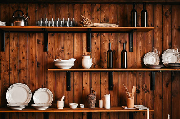 Rustic wooden kitchen shelves displaying various dishes, wine bottles, and cooking utensils