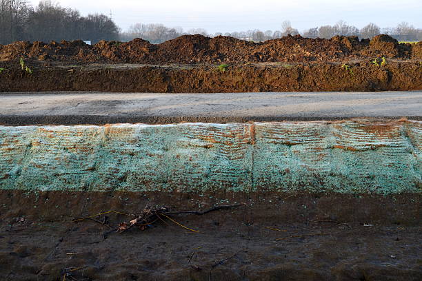 A gravel path for walkers and cyclists is frozen jute netting retaining earth soil from flowing water stream on a sunny day