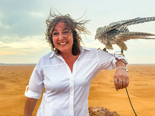 Cute woman holding a falcon. Desert trips and safari tours ara a common traditional action for Dubai residents and tourists. Famous red dunes of Dubai provide exotic feeling.
