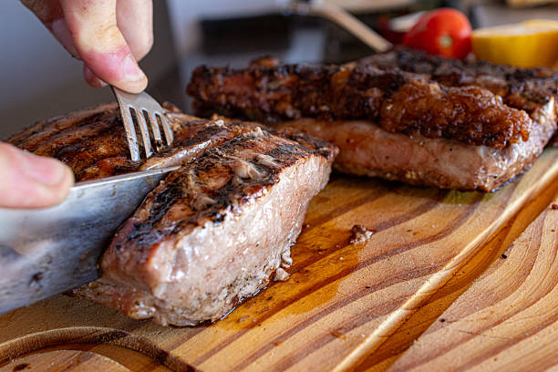 Hand carving juicy grilled picanha steak on rustic wooden board