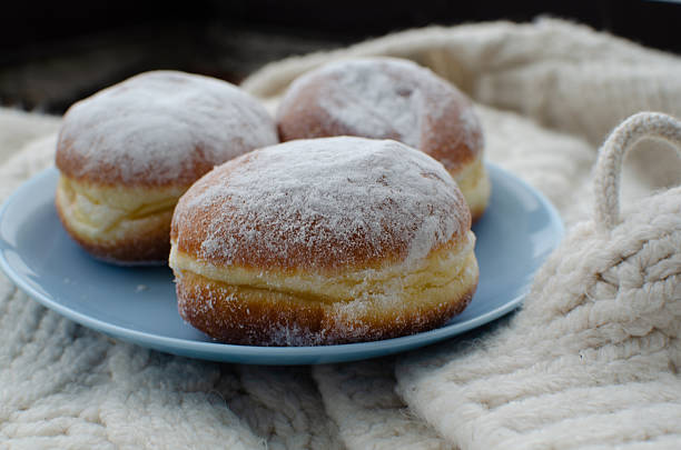 Three doughnuts rest on a plate, dusted with sugar. Creamy filling. Great for food blogs