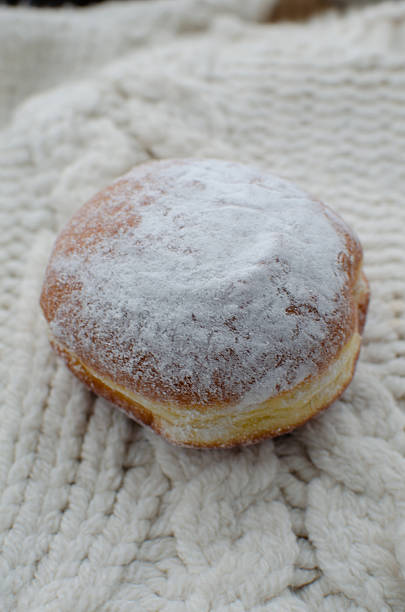 A delicious donut sits on a classic white cable knit fabric. Use for bakery and sweets concept