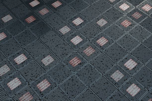 Abstract architectural background showing a repetitive metal grid facade with perforated and slatted panels, some backlit with soft white and red light, no people.