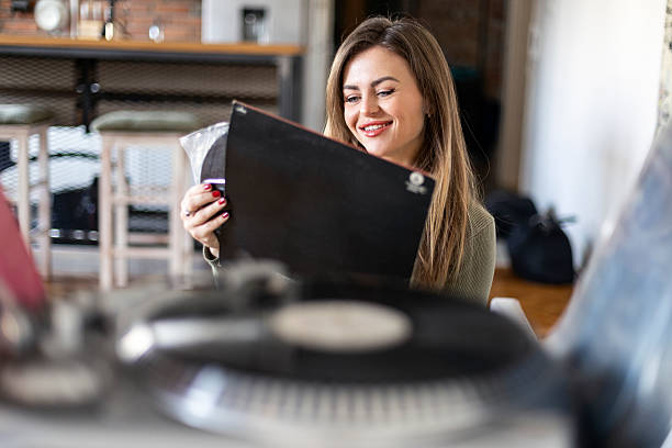 Young woman listening to a music record on a modern turntable. About 30 years old, Caucasian female.