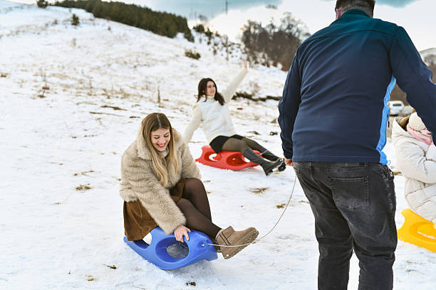 Family tobogganing down a snowy hill during winter vacation