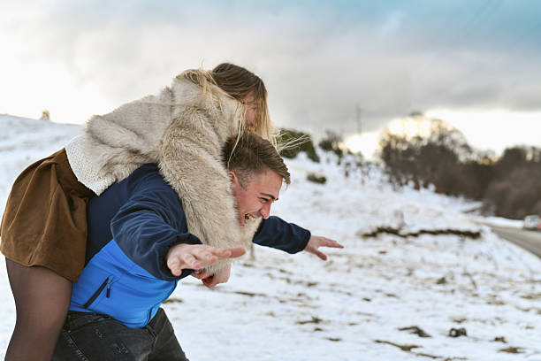 Mother playfully hurling a snowball at her laughing child in a snowy park, sharing joyful winter bonding and active outdoor fun among trees on a bright cold day