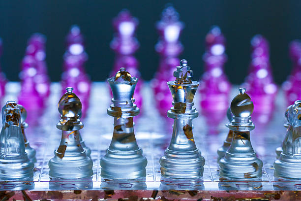 a modern artistic chess set with translucent acrylic pieces (clear and magenta), embedded gold leaf fragments, a transparent board with grid lines and letter/number markings, placed on a white circular table under cool blue lighting