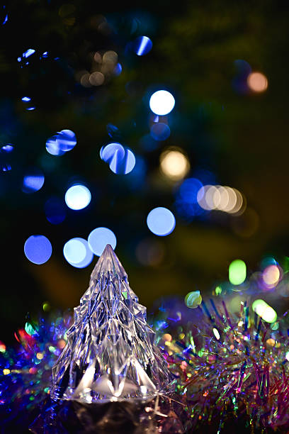 Crystal Christmas tree decoration glittering on tinsel with soft blue bokeh lights in background