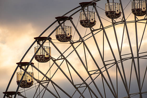 A ferris wheel pauses to load passengers in sunset light.