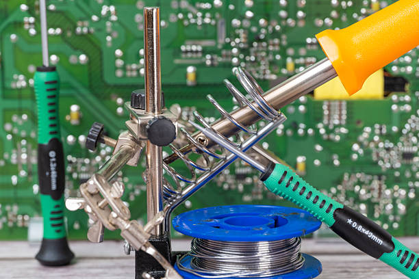 A close-up of an electrical circuit board with a soldering iron and screwdrivers