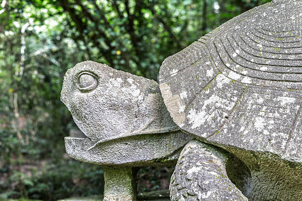 Italy - Bomarzo - Sacro Bosco - Tortoise sculpture with world sphere supporting statue base, carved in peperino among forest greenery