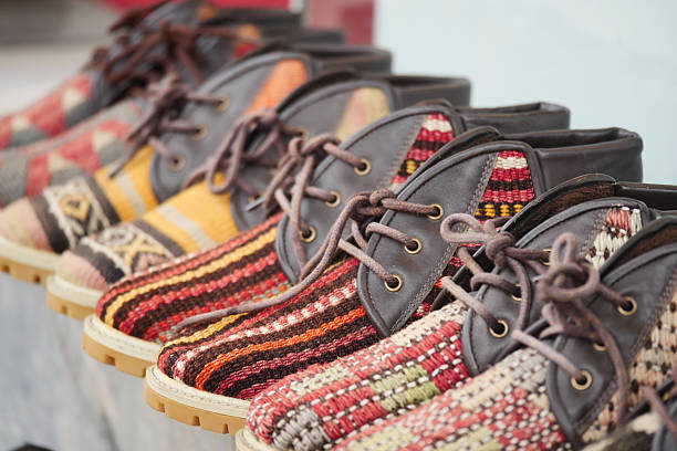 Handcrafted shoes with vibrant patterns are arranged neatly at a market.
