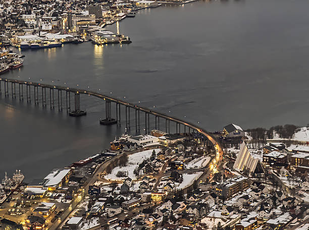 Tromso, Norway - December 22, 2025: Winter polar night. Tromso bridge linking the Island with the mainland and Arctic Cathedral seen from Fjellheisen, the mountain lift, up Storsteinen mountain