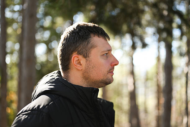 Man in black jacket standing outdoors in a nature park, observing the natural environment