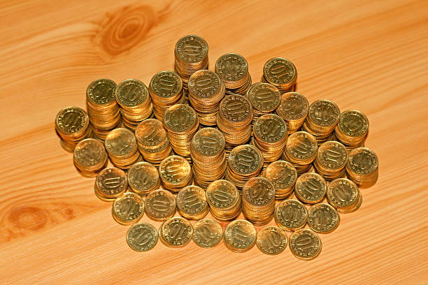 Stacks of Golden Coins With Ten Face Value at Wooden Table