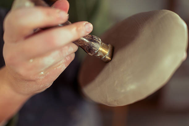 Closeup shot of hands of unrecognizable female artisan pressing dried flowers onto ceramic leaf plate