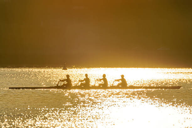 Side view of a coxless four on a river in a rowboat rowing on a race.