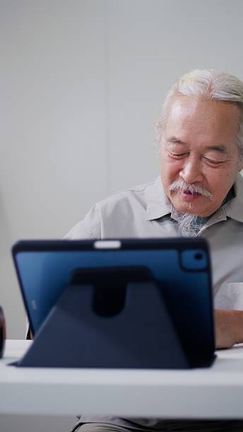 Senior Asian Man Taking Online Retirement Investment Course in Sustainable Home Office.