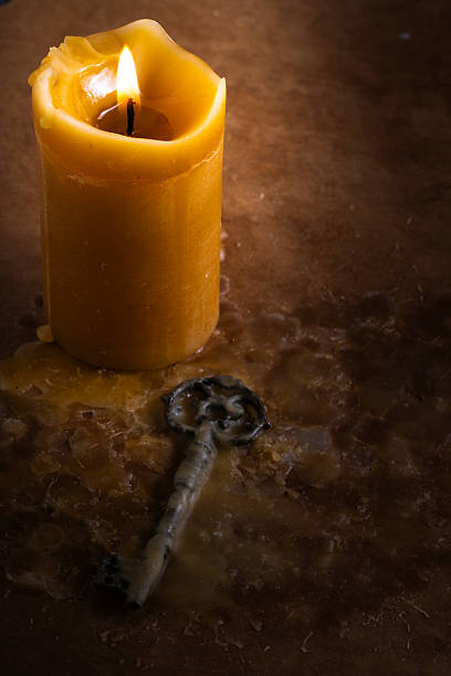 Candle with vintage key on dark background. Tinted