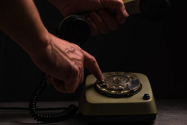 Retro telephone on black background. Closeup mans hand holding handset