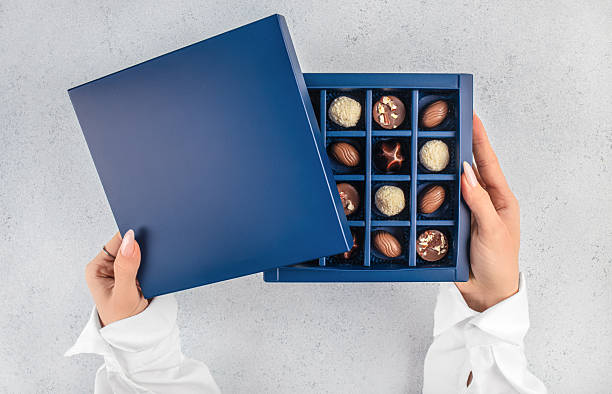 Hands holding open luxury chocolate gift box with assorted pralines