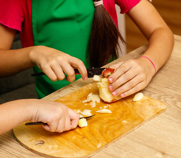 A girl is cutting an apple with a knife