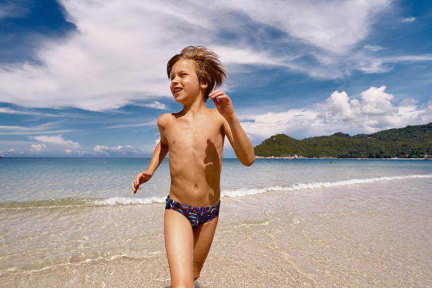 Playful boy having fun while running during summer day on the beach. Copy space.