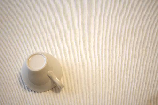 Upside down white cup placed on table with clean white background and copy space. Minimalist simple living concept representing pause, calm lifestyle, simplicity and modern visual balance.