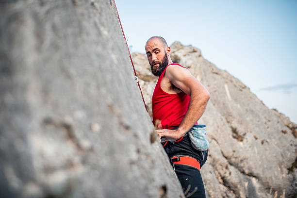 Concentrated male rock climber making a difficult move on a steep stone wall. Symbol of overcoming obstacles, determination an inner strength
