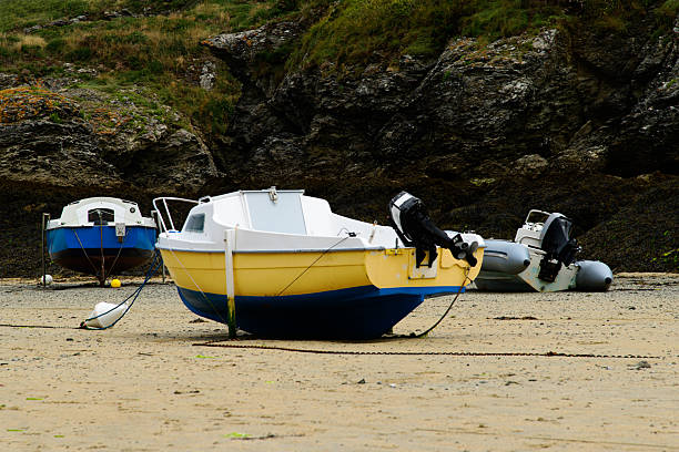 Mousehole harbour and village, with boats moored at low tide, Cornwall, England