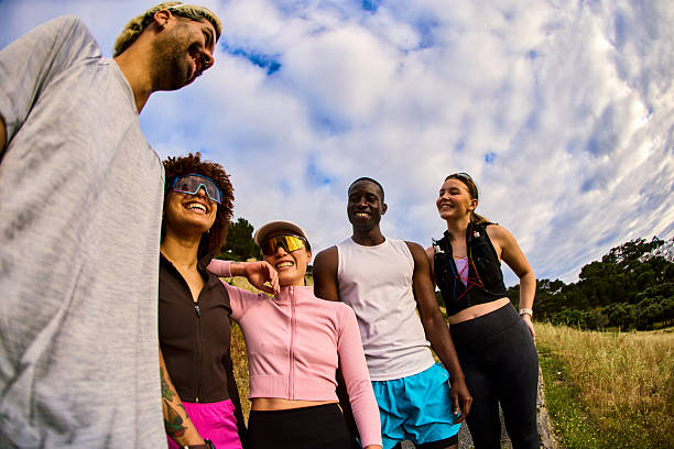 Group of diverse runners laughing together after successful morning training session outdoors