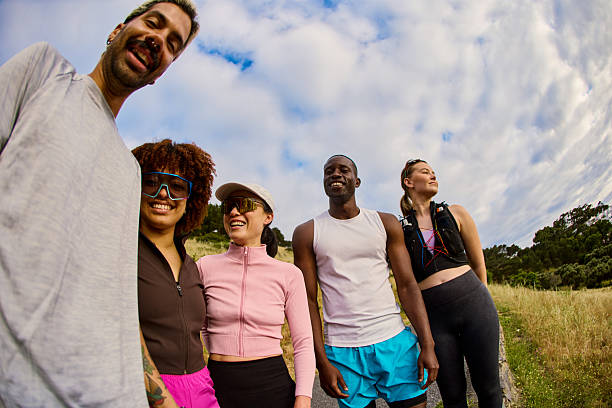 Group of diverse runners laughing together after successful morning training session outdoors