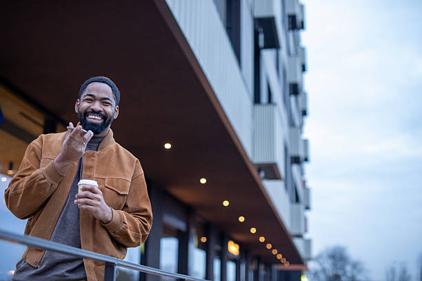 Black man smiling holding coffee and smartphone downtown