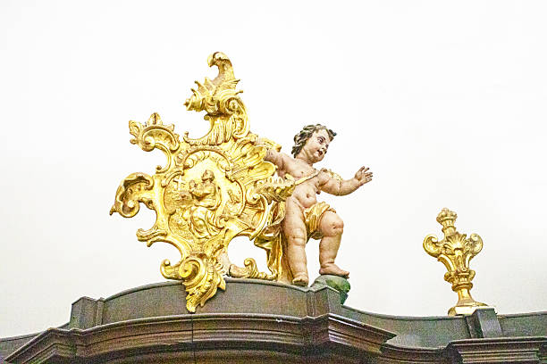 Decorative gilded frame element in the Baroque or Rococo style with a statue of Cupid on a light background