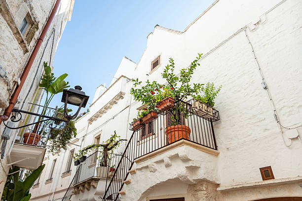 View of one of the many beautiful little alleys with beautifully designed balconies and houses in Alberobello, a town known especially among tourists for its numerous trulli houses.