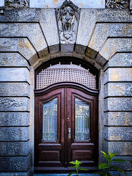ornate wooden door with decorative glass panels and stone arch featuring lion head sculpture, historic european building entrance front view